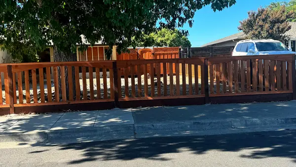 Redwood picket fence with arched sections along a residential street