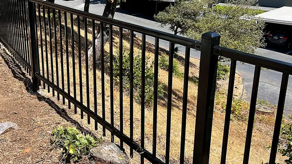 Black iron security fence installed on a slope beside an apartment complex